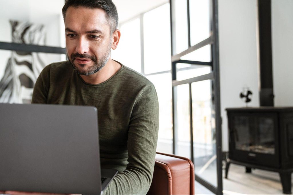 Hombre revisando un contrato en su laptop para firmarlo electrónicamente desde casa